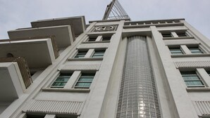 A tall building with a central glass tower, multiple windows, and a distinctive logo on the facade. - Hotel Plaza del Arco Express (Monterrey)