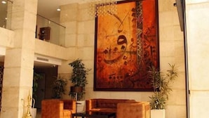 A lobby with a large abstract painting, a seating area with sofas, and a staircase. - Sofi Hotel (Oran)