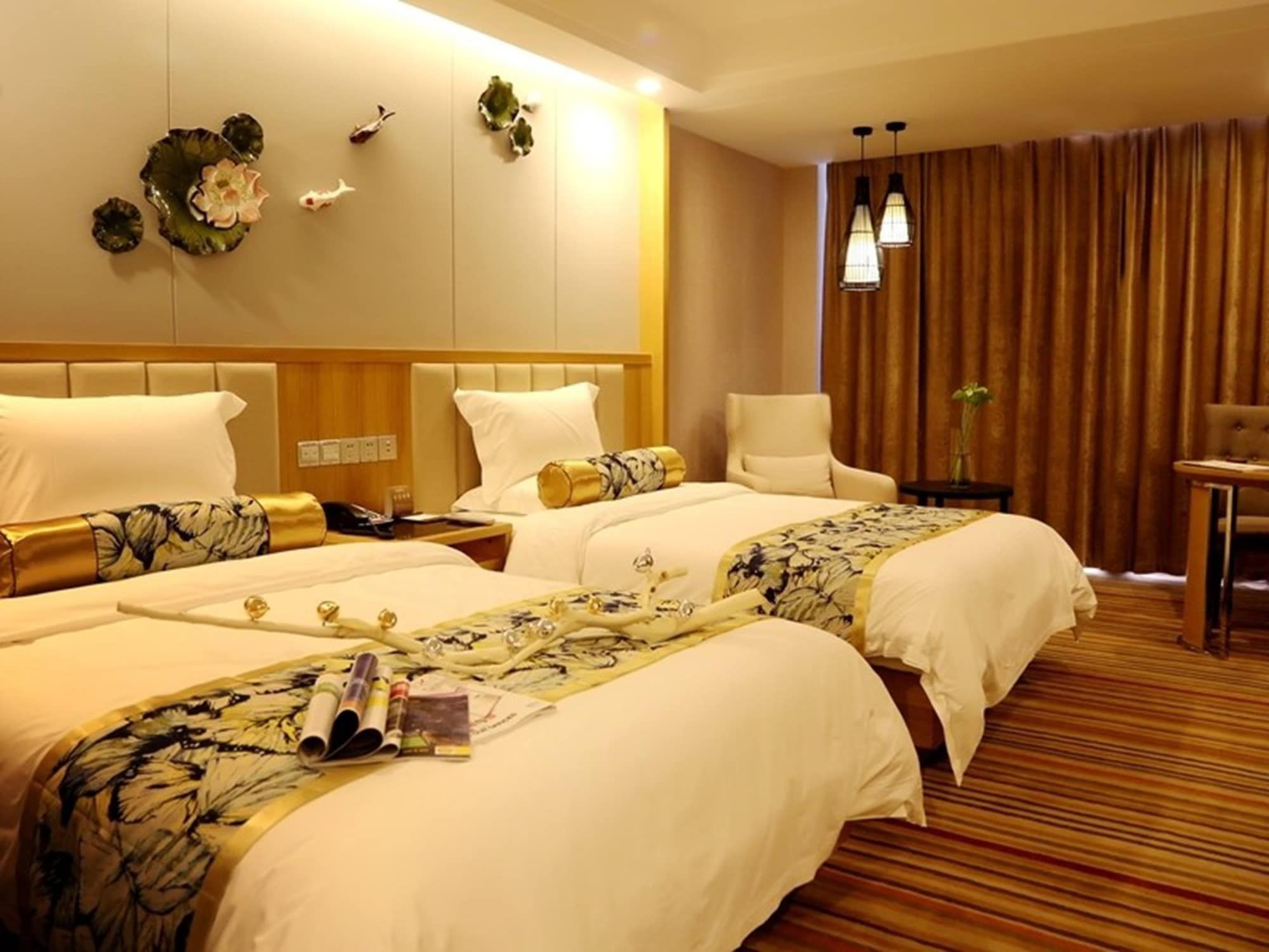 A hotel room with two beds, a sitting area, and a view of the city.