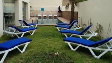 Una piscina al aire libre, sillones reclinables de piscina