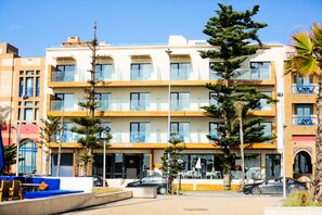A multi-story hotel with balconies, outdoor seating, and a parking area. - Hotel Coté Océan Mogador (Essaouira)