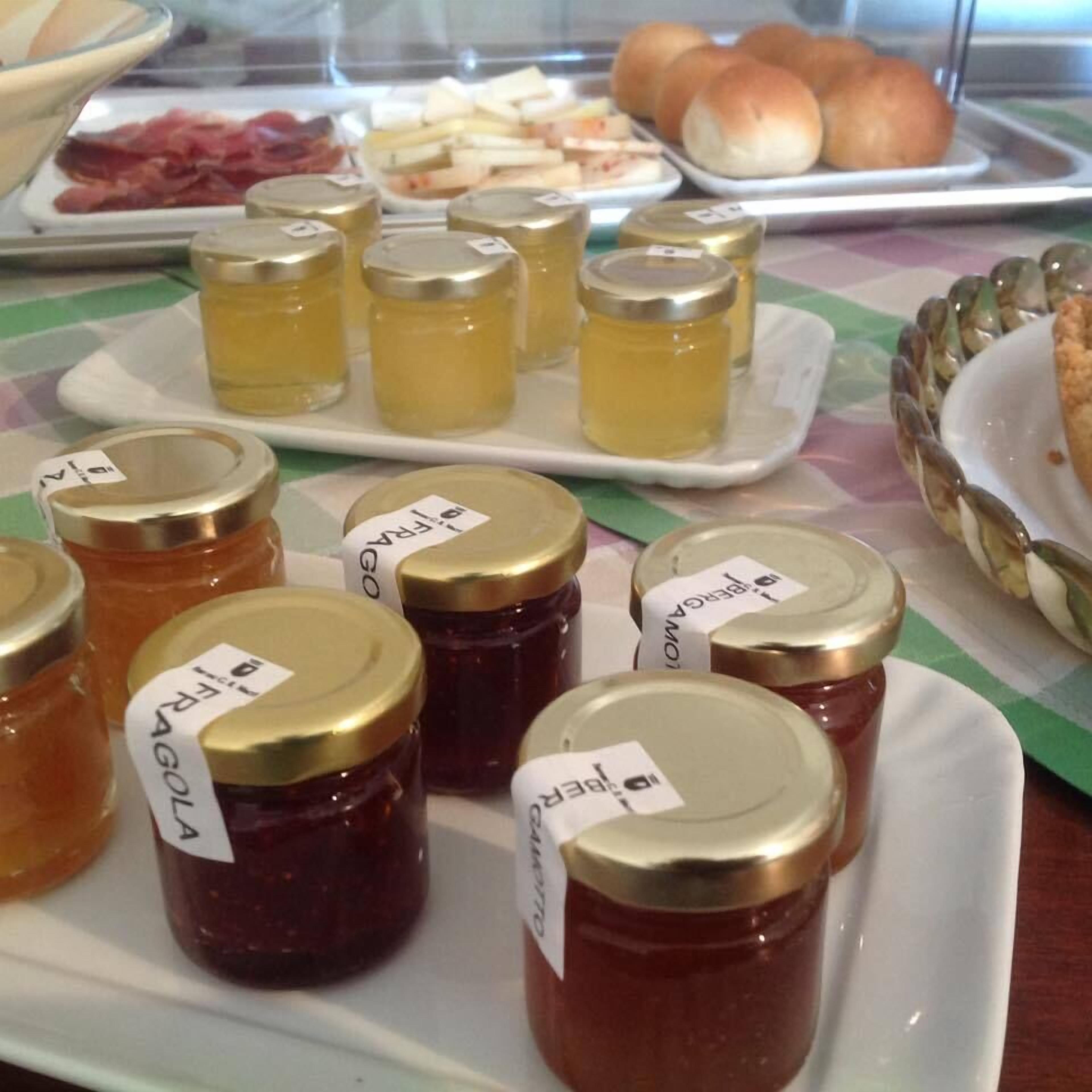 Een buffet met diverse etenswaren, waaronder potjes jam, vleeswaren en gebak.