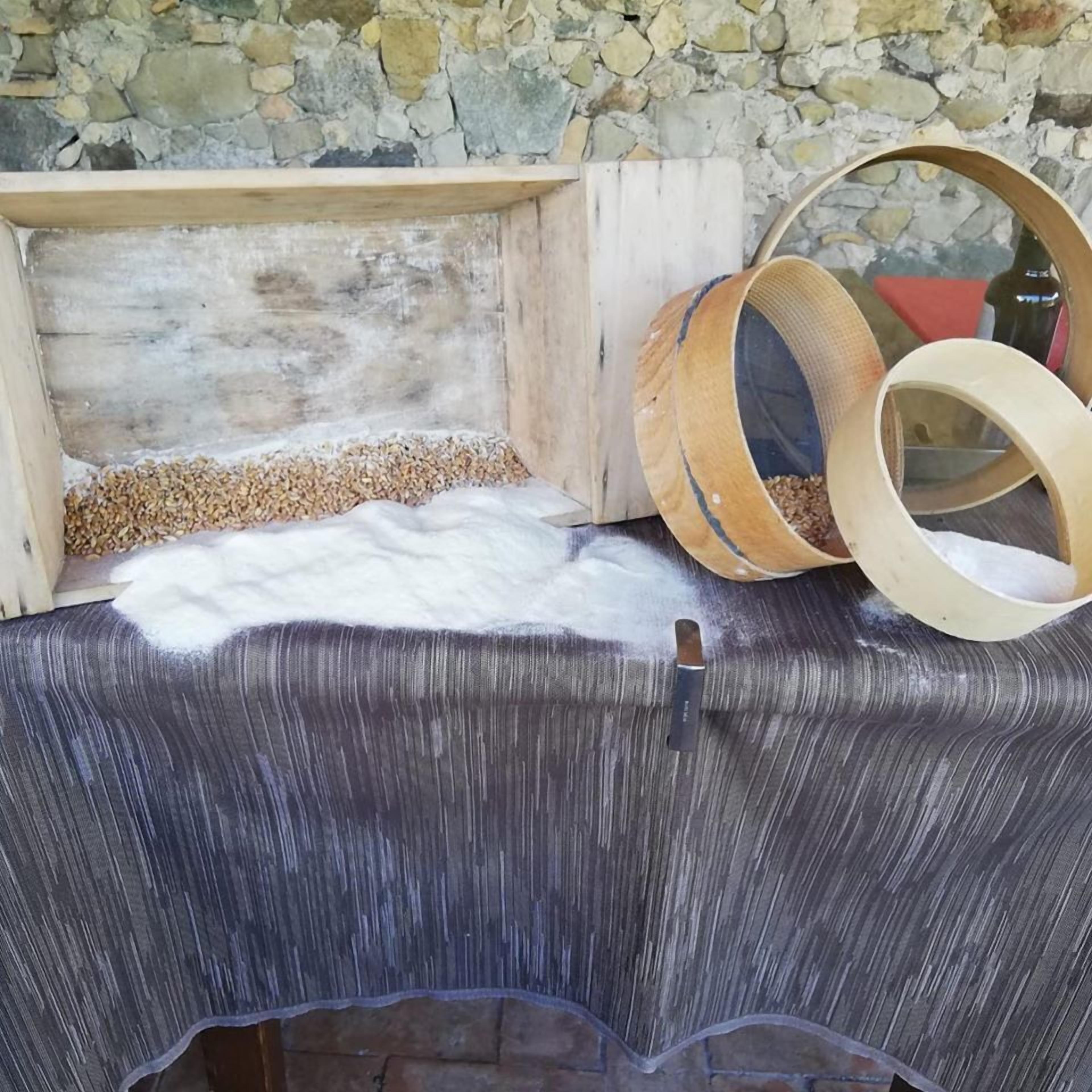 Una preixosa prestatgeria de fusta amb un fons de pared de pedra, una taula amb tela blanca i gra dispers, i dos cuplets de fusta.