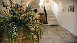 Un pasillo con un arreglo floral grande, una escalera y un piso de piedra.