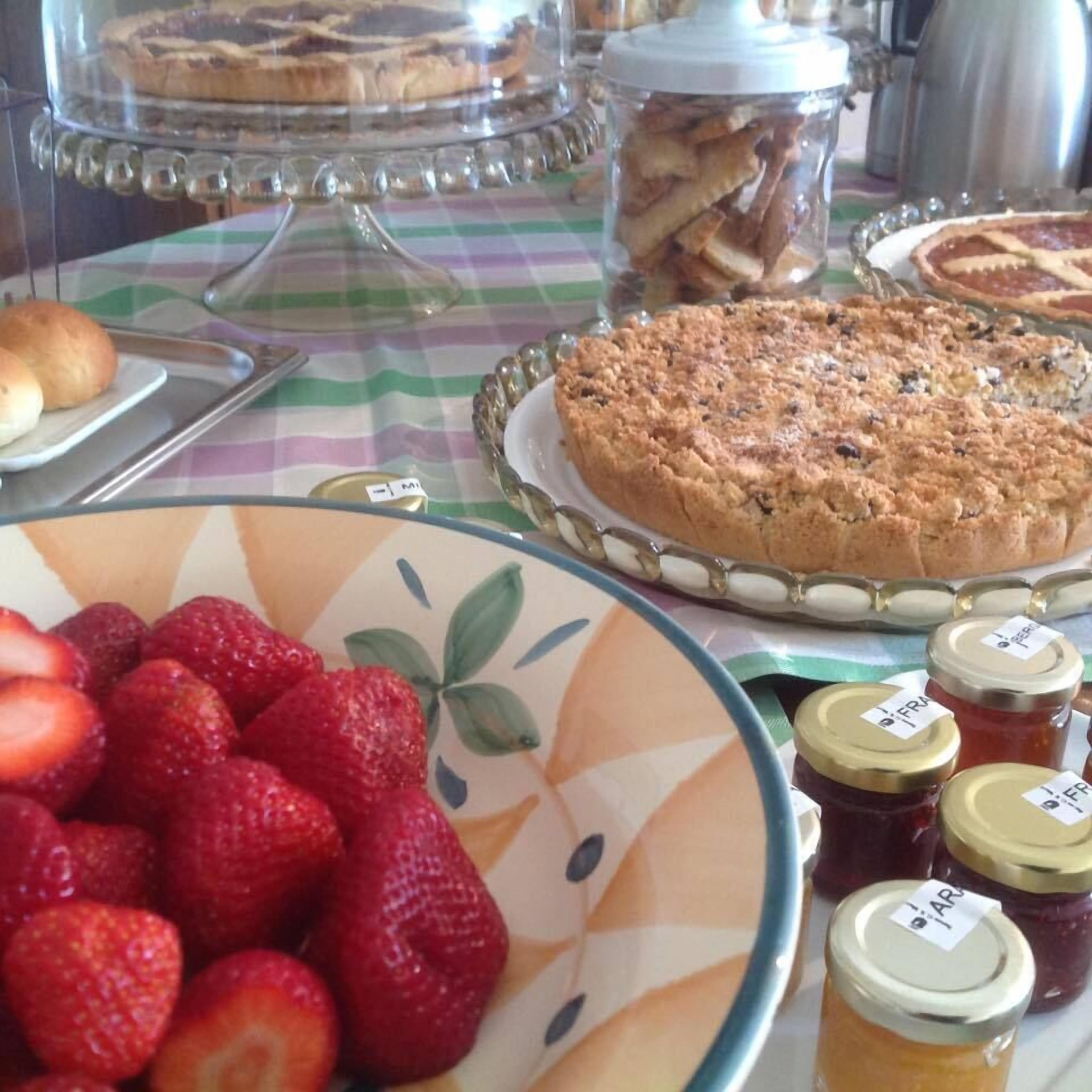 A buffet table with various food items including a fruit platter, cakes, and jars of jam.