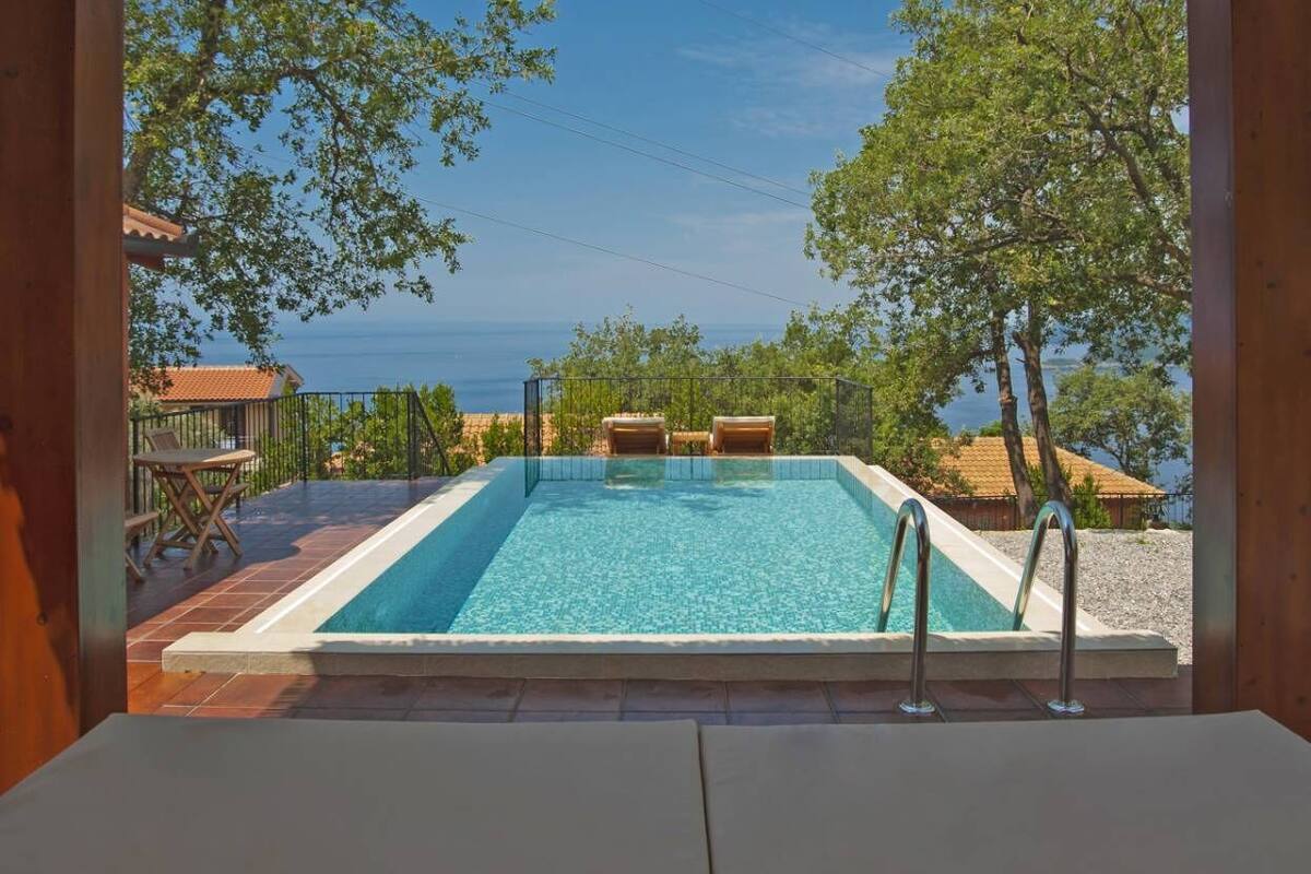 A wooden cabin with a pool and a view of the sea.