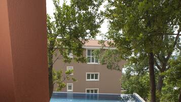 Un patio con mesa y sillas, con vistas a una piscina y un edificio con ventanas.