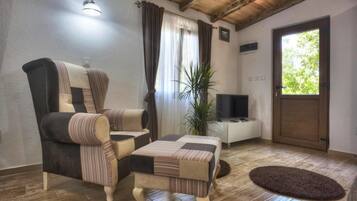 A living room with a sofa, ottoman, and a television.