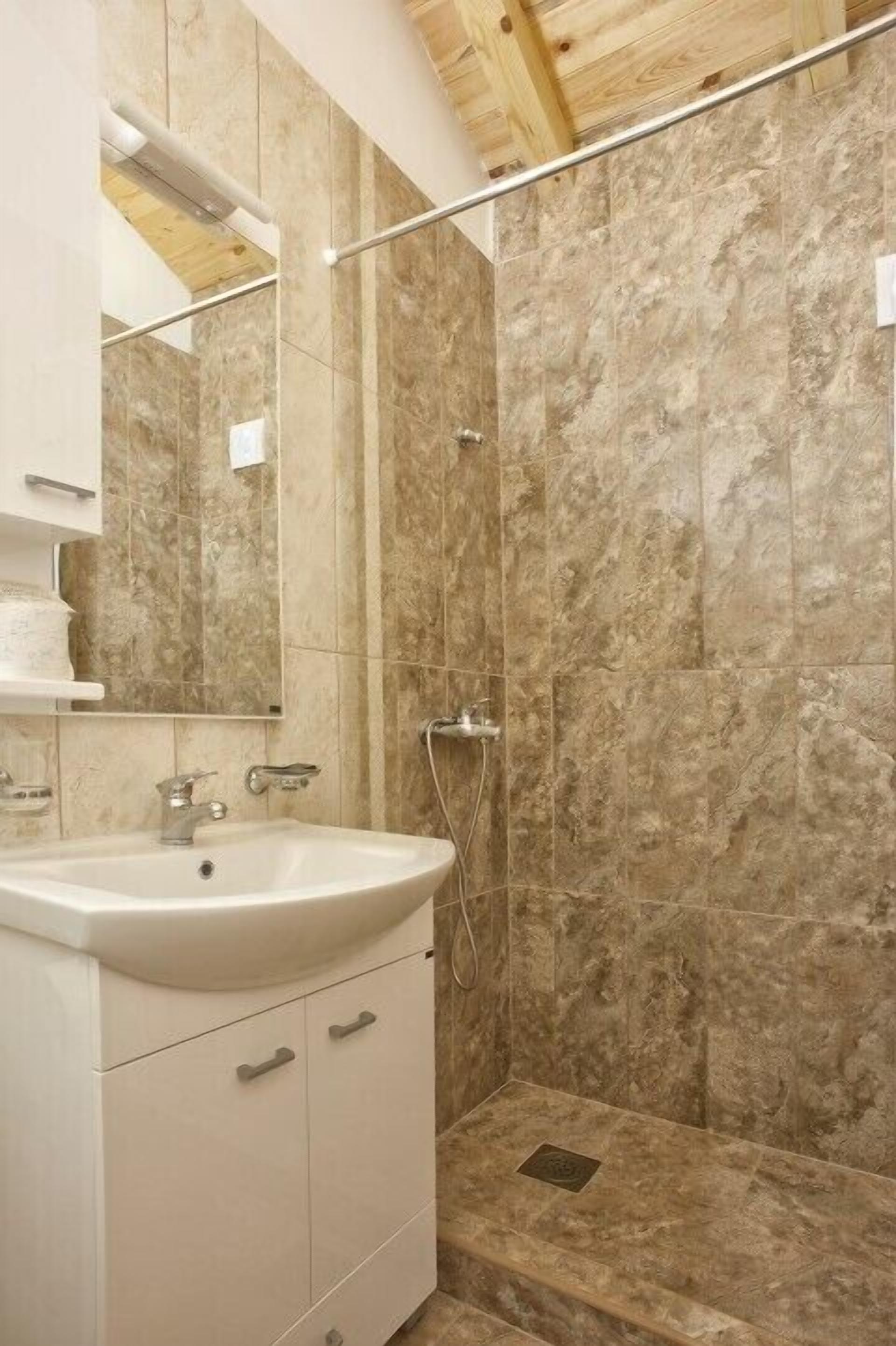 Un baño con lavamanos, espejo y ducha.