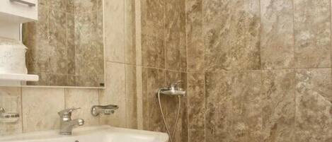Un baño con lavamanos, espejo y ducha.
