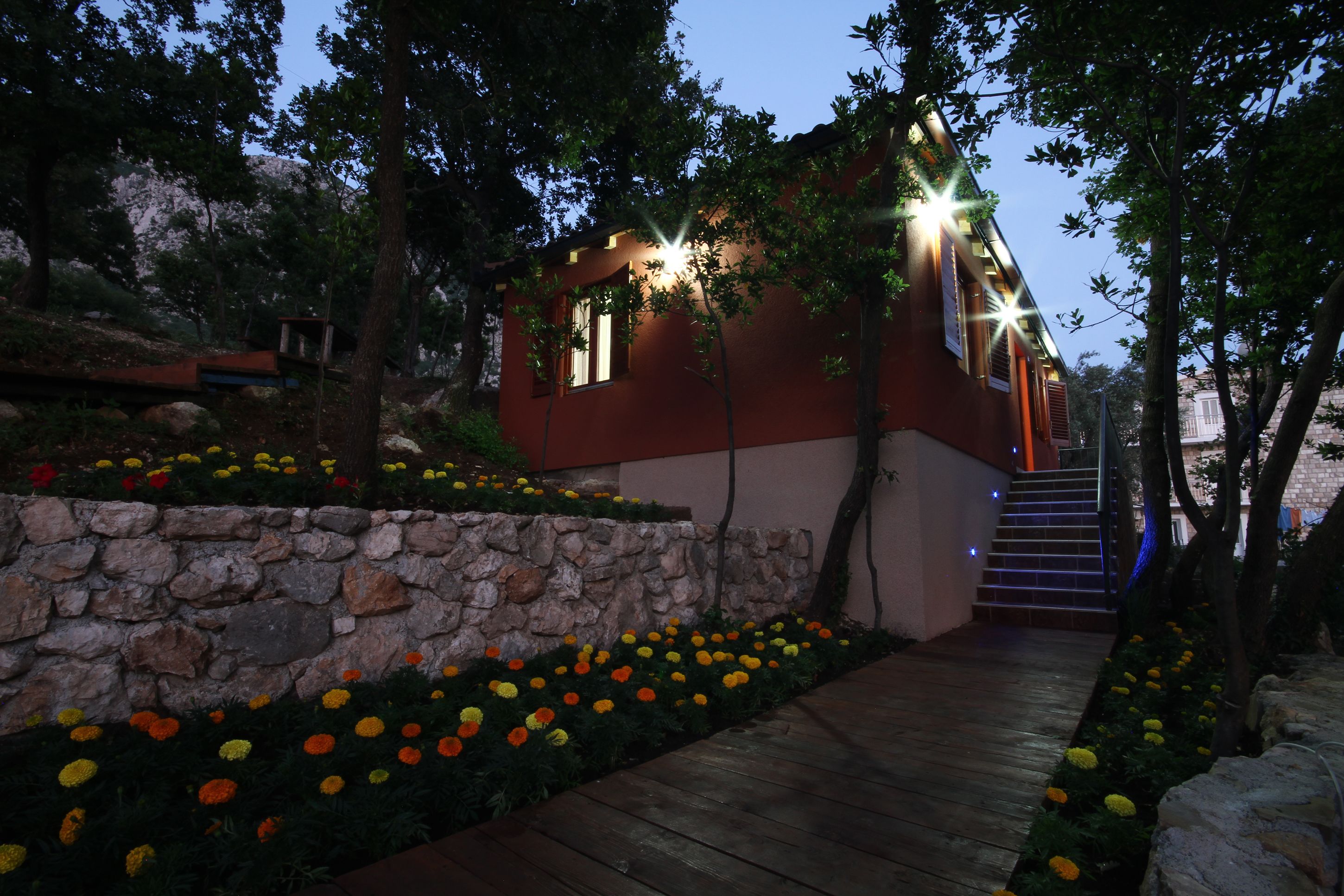 Una casa moderna con un muro de piedra y coloridos jardines florales.
