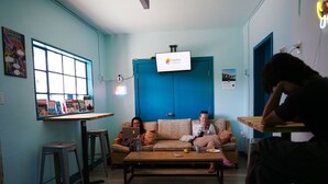 Una habitación con pared azul, una mesa de centro de madera, un sofá y un televisor montado en la pared.