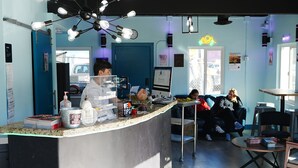 Una cafetería con mostrador, zona de estar y letrero de neón.
