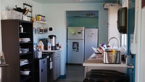 Una cocina compacta equipada con refrigerador, cafetera y distintos utensilios de cocina.