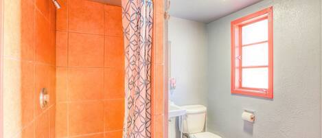 Un baño con ducha, inodoro y lavabo.