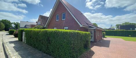 A residential house with a red brick exterior, a tiled roof, and a paved driveway.