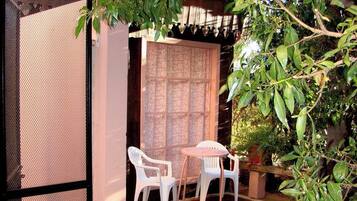 An outdoor patio area with a mesh screen, two white plastic chairs, and a small table.