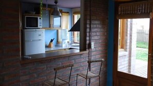 A kitchen with a microwave, refrigerator, and bar stools. - La Floridita Puerto Piramides (Puerto Pirámides)