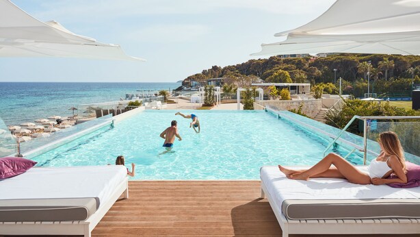 Zona de piscina con sillones de descanso y vista al mar.