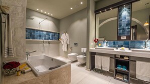 Un baño moderno con una bañera amplia, un inodoro separado y un tocador con espejo.