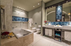 A modern bathroom with a large bathtub, a separate toilet, and a vanity with a mirror. - Forte Village Resort Villa Del Parco & Spa (Pula)