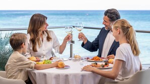 Un grupo de personas cenando en una mesa con vistas al océano.