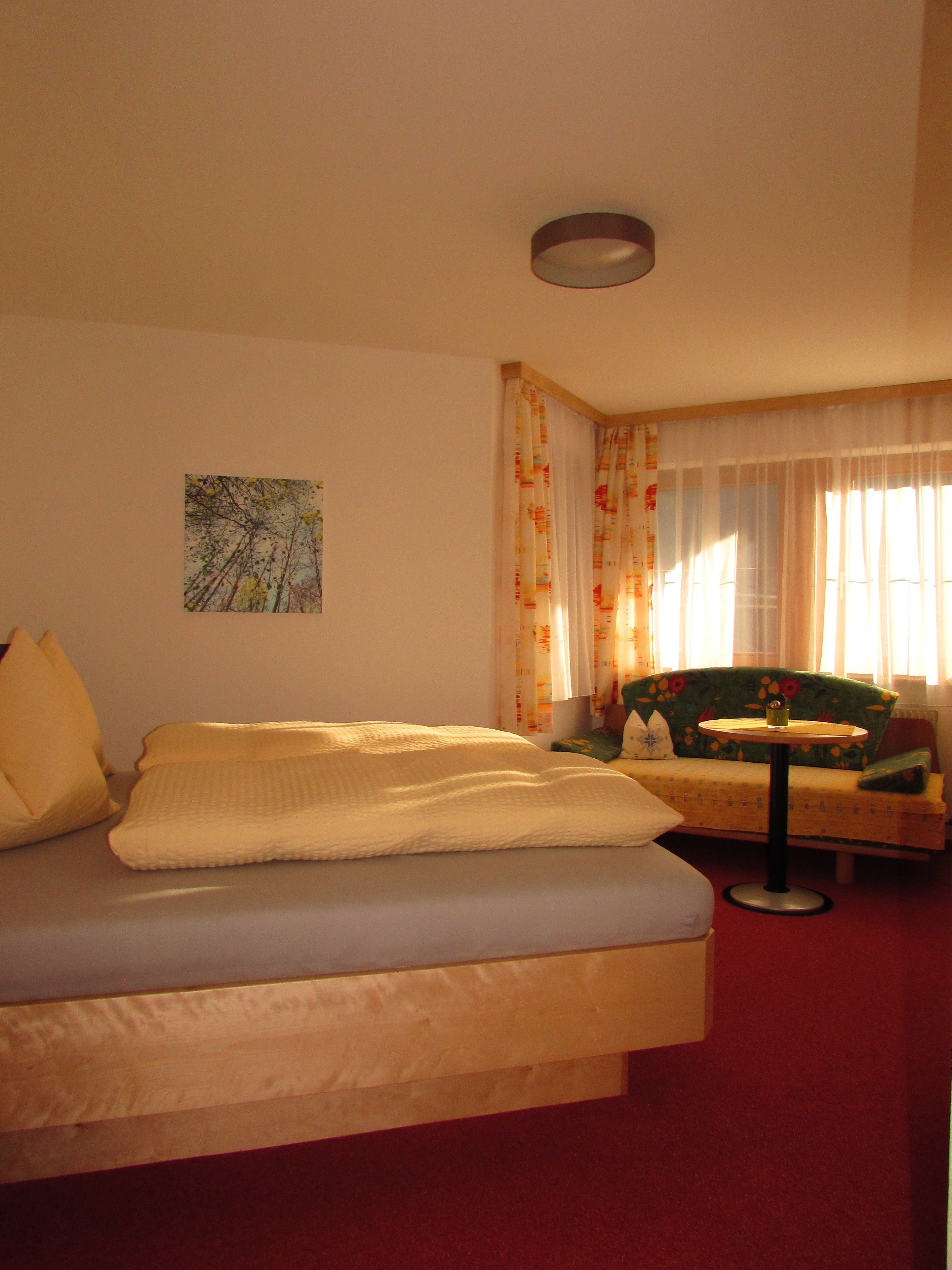 Une chambre à coucher avec un lit, une petite table, un canapé et un tableau accroché au mur.