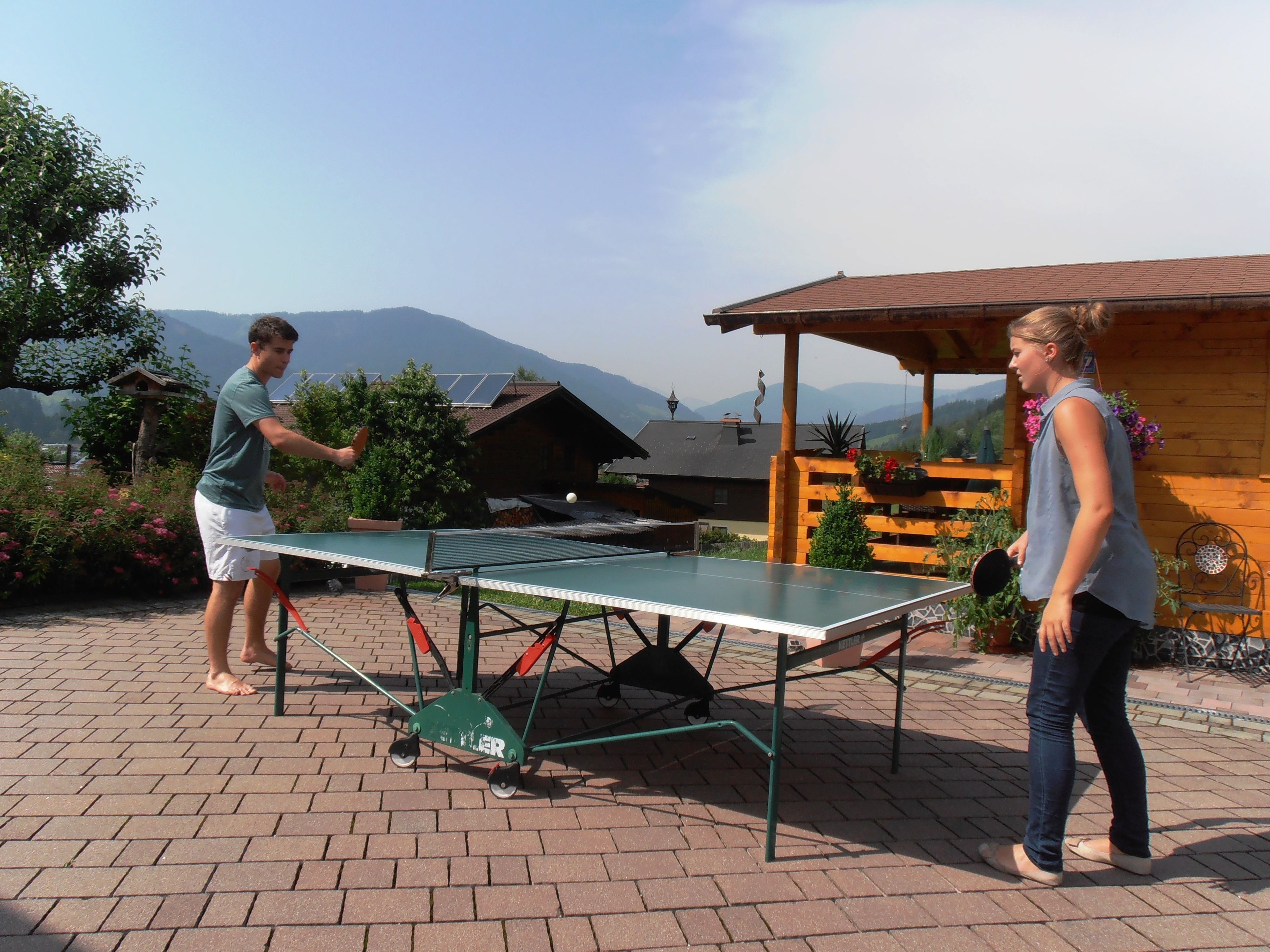 A ping pong table set up outdoors with a mountainous backdrop.