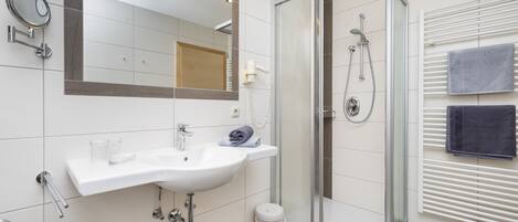 A modern bathroom with a white sink, mirror, and shower.