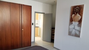 A bedroom with a bed, wardrobe, and a painting on the wall. - Appartements bon Secours (Peruwelz)