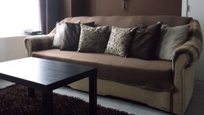 A living room with a sofa, a coffee table, and a rug. - Appartements bon Secours (Peruwelz)