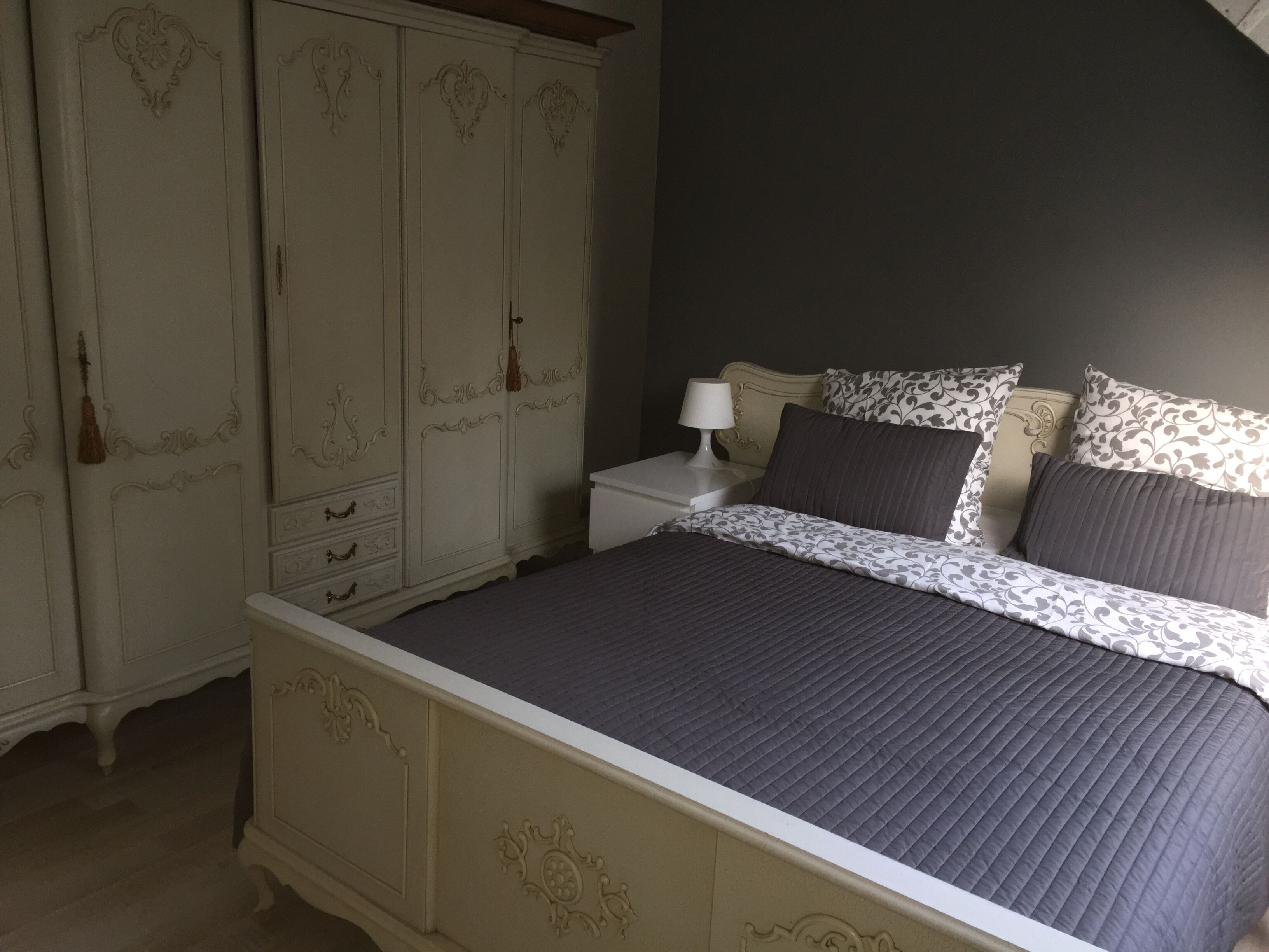 A bedroom with a bed, nightstand, and a wardrobe.