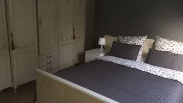 A bedroom with a bed, nightstand, and a wardrobe.