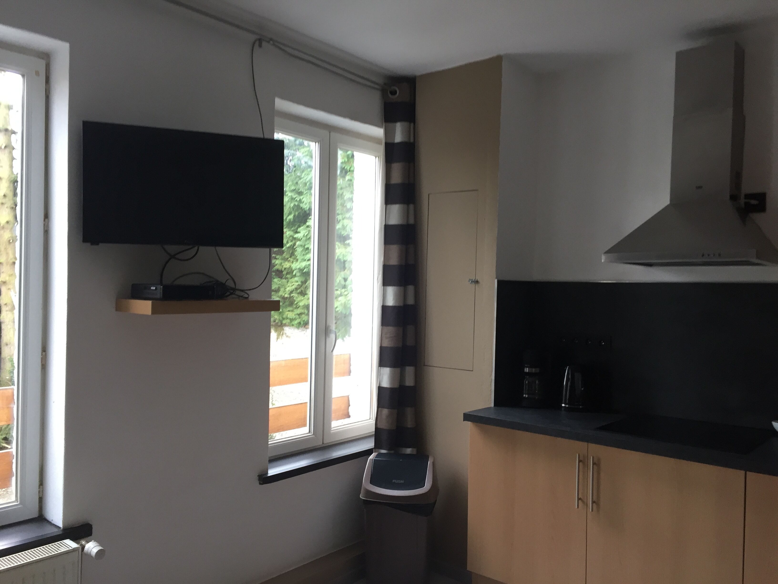 A modern kitchen with a built-in oven, a microwave, and a stove. There is a window with a view of greenery outside.