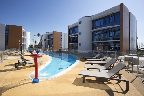 A rooftop pool area with lounge chairs and a water feature. - Marineland Resort (Antibes)