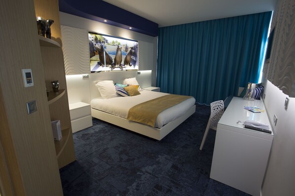 A modern hotel room with a bed, bedside tables, a desk, and a television.