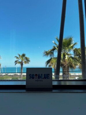 A sign for the So Blue Hotel with a view of palm trees and the ocean. - Marineland Resort (Antibes)