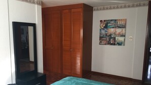 A bedroom with a bed, a wardrobe, a mirror, and a wall with a travel-themed picture. - Departamento en Centro de Toluca (Toluca)