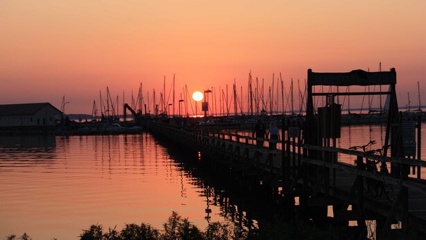 A pier with boats docked at sunset.
