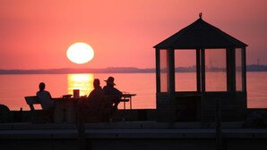 A gazebo overlooking a sunset over a body of water.