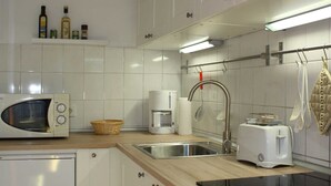 A modern kitchen with white cabinets, a microwave, a coffee maker, a toaster, and a sink.