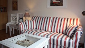 A striped sofa, a small table with a lamp, and a framed picture on the wall.