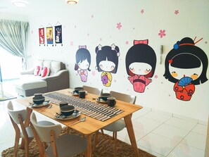 Un comedor con una mesa de madera dispuesta para dos personas, sillas y una pared decorada con adhesivos de estilo anime.