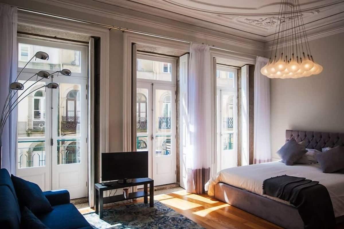 A bedroom with a large bed, a TV, and a sofa.