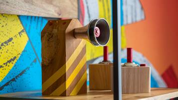 Un objeto de madera con una parte superior cilíndrica y un logotipo circular rojo y blanco, sobre una superficie de madera.