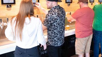 Un espace bar avec un comptoir, des verres et un téléviseur diffusant des événements sportifs.