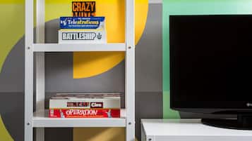Una estantería blanca con varios juegos de mesa y un televisor sobre un soporte.