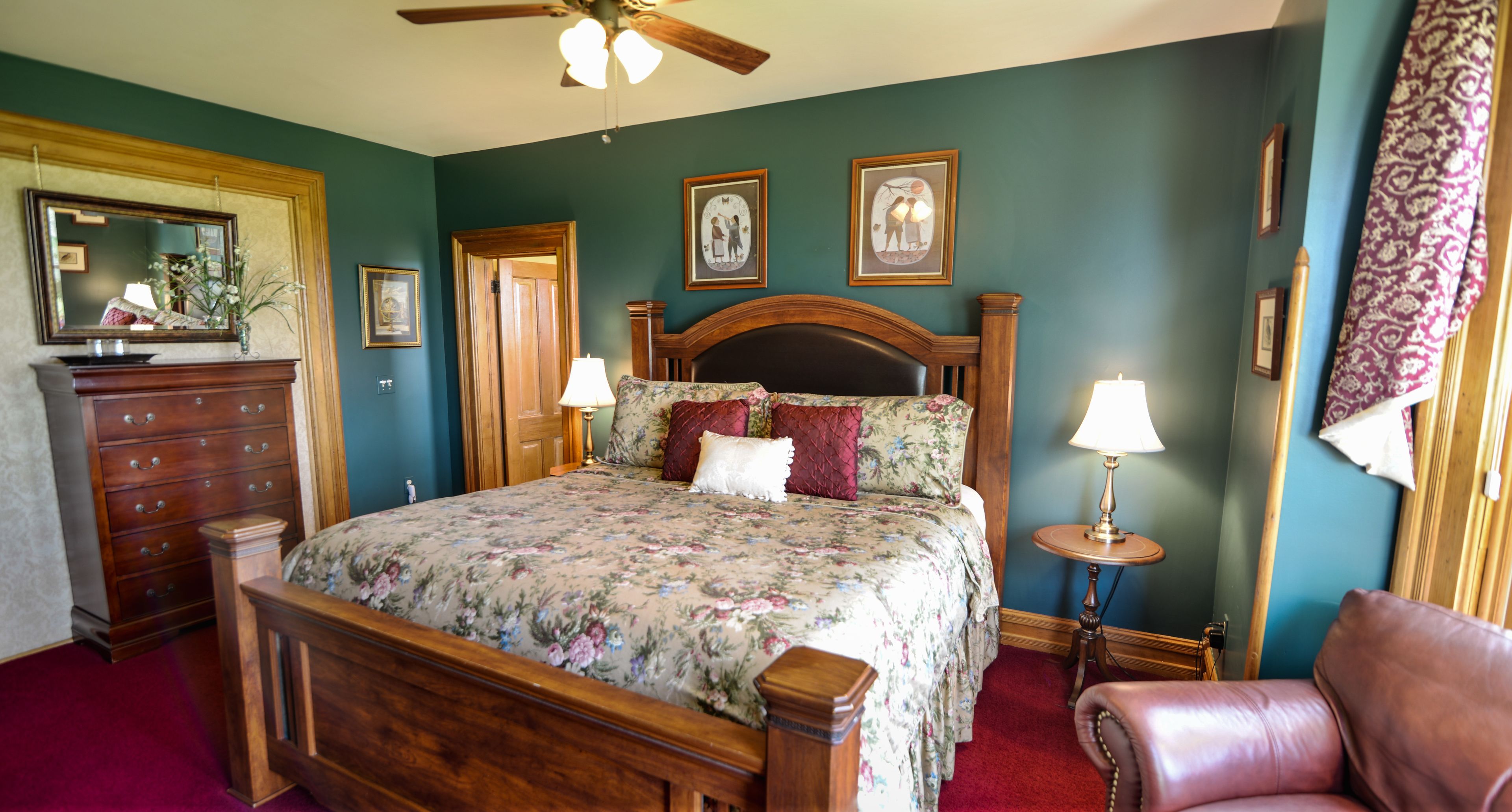 A bedroom with a wooden bed, two bedside tables with lamps, a dresser, and a chair.
