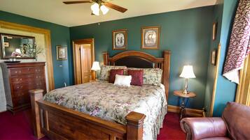 A bedroom with a wooden bed, two bedside tables with lamps, a dresser, and a chair.