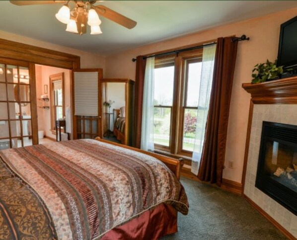 A bedroom with a large bed, a fireplace, and a view of the outdoors through a sliding glass door.